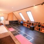 Moderne Heimfitnessstudio mit Trainingsgeräten, Matten und einem offenen Bereich für Übungen.