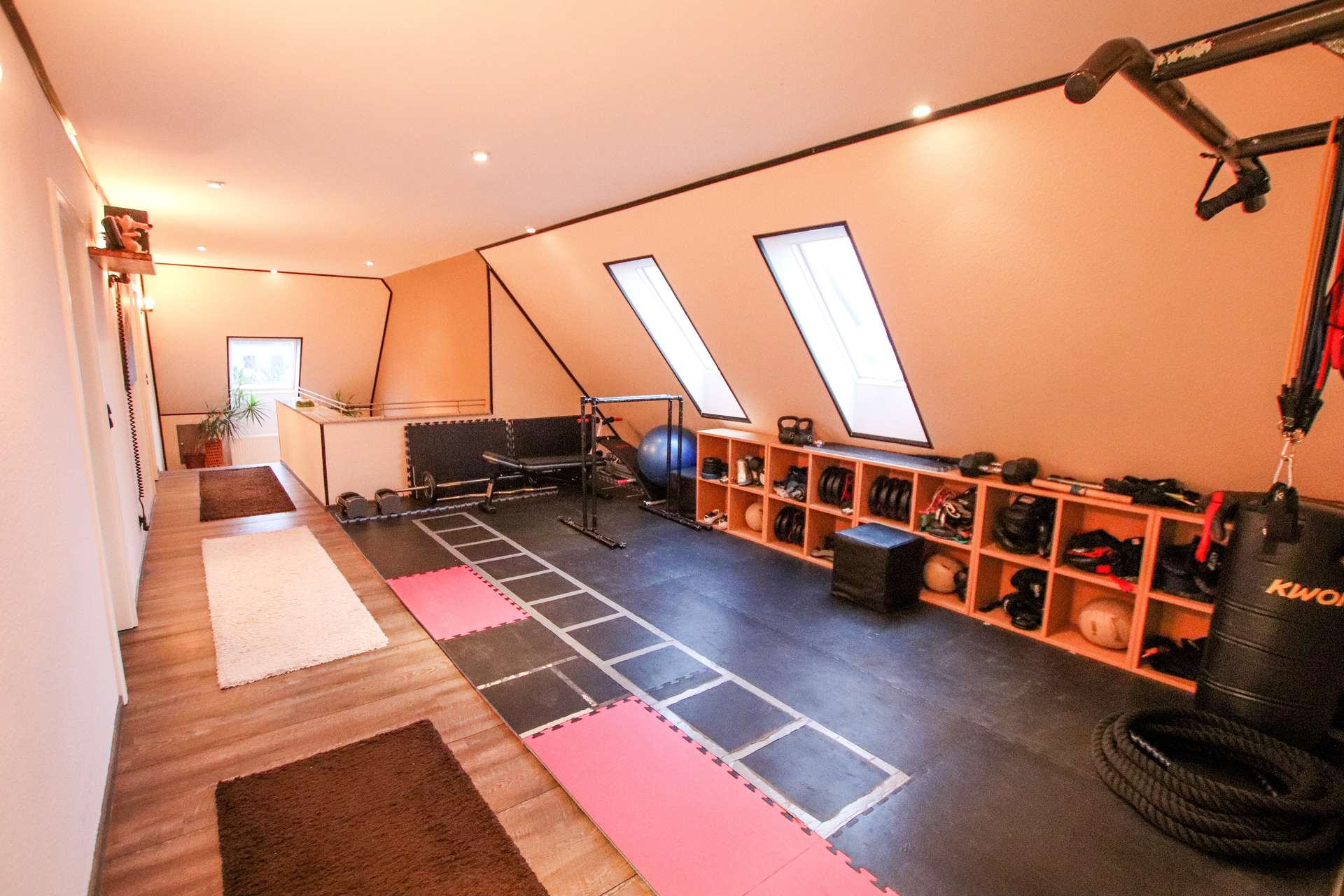 Moderne Heimfitnessstudio mit Trainingsgeräten, Matten und einem offenen Bereich für Übungen.