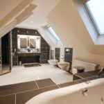 Modernes Badezimmer mit Dachfenstern, freistehender Badewanne, Doppelwaschbecken und eleganten Fliesen.