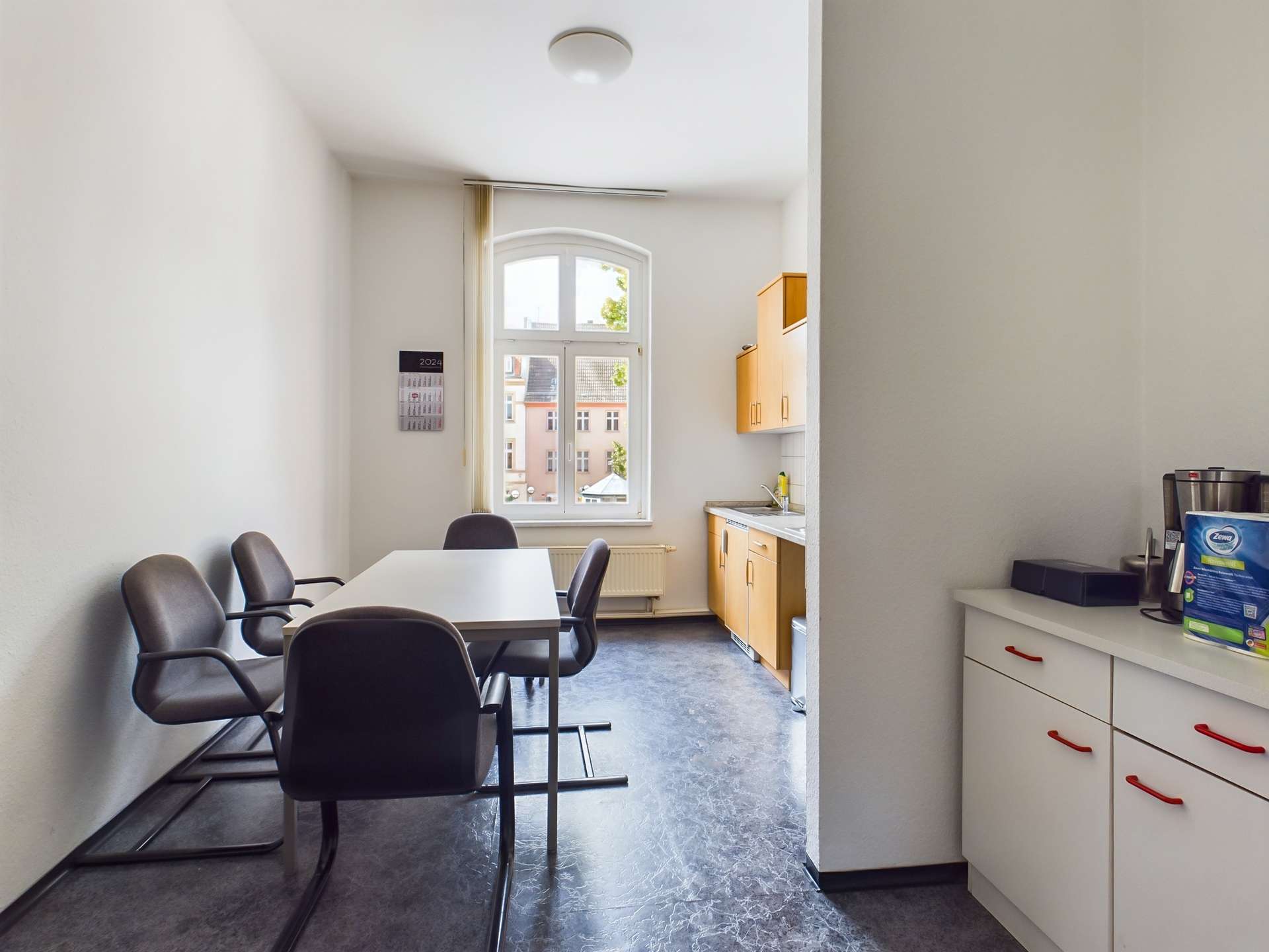 Helle Küche mit einem Tisch und Stühlen, Fenster mit Ausblick und modernen Küchenschränken.