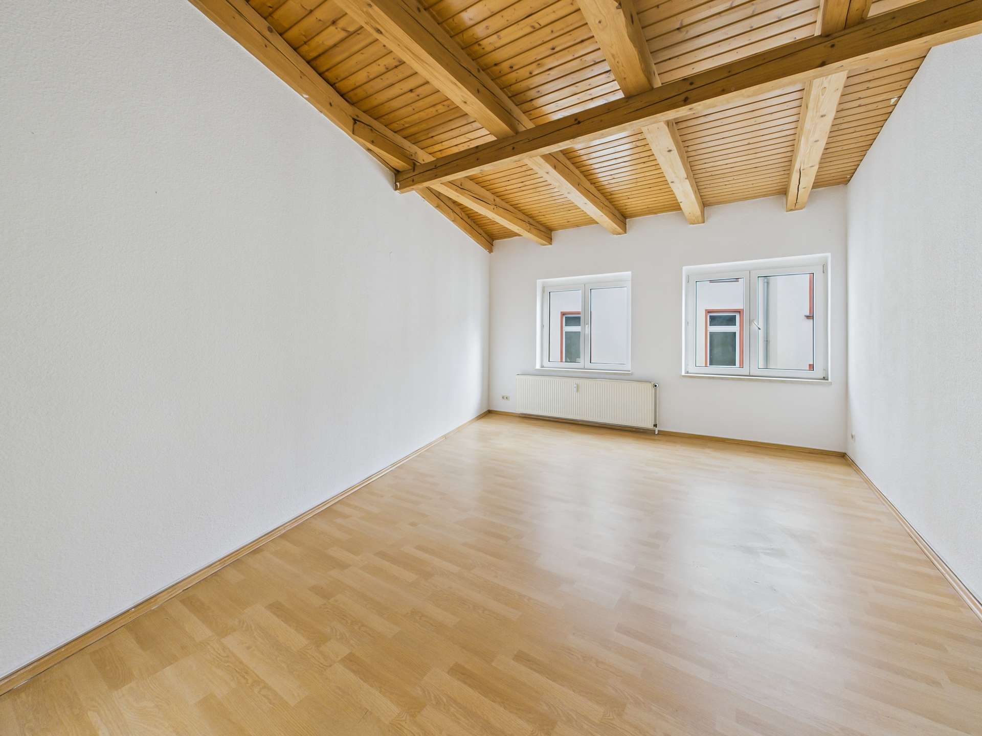 Heller Raum mit Holzdecke, großen Fenstern und hellem Parkettboden, ideal für verschiedene Nutzungsmöglichkeiten.