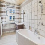 Helles Badezimmer mit Badewanne, Dusche, modernem Waschbecken und groĂen Fenstern fĂŒr Tageslicht.