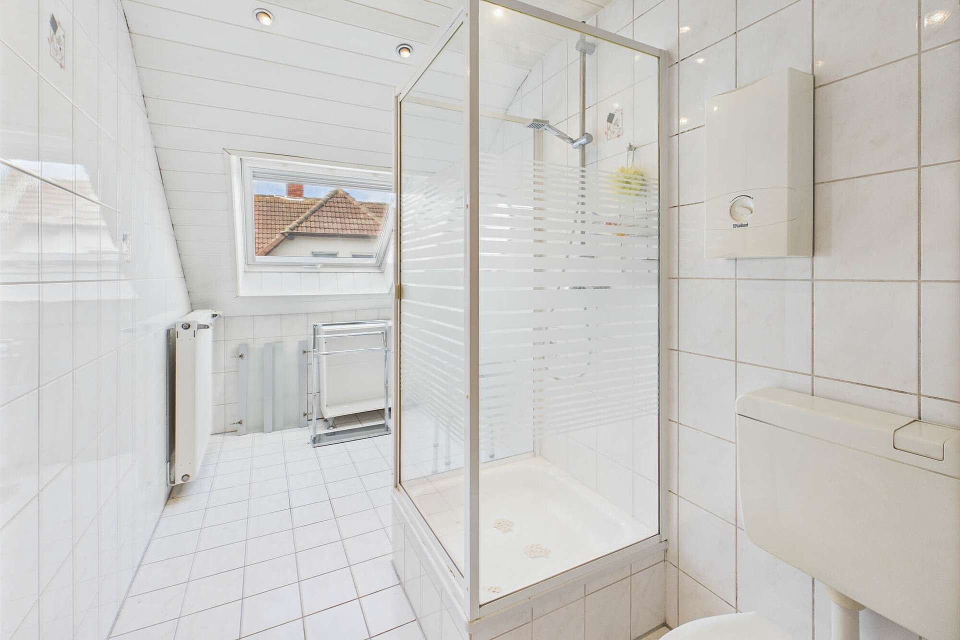 Modernes Badezimmer mit Duschkabine, WC und Fenster, gefliest in Weiß.