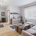 Heller Wohnraum mit Sofa, Couchtisch und BĂŒcherregal, dekoriert mit Pflanzen und persönlichen Bildern.