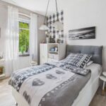 Ein modernes Schlafzimmer mit einem Bett, dekorativen Kissen, einem Fenster mit grĂŒner Aussicht und stilvollen WĂ€nden.