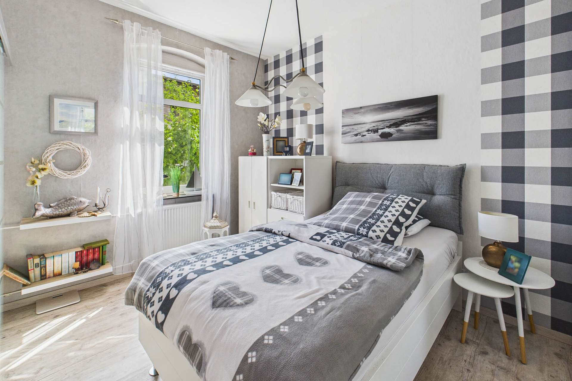 Ein modernes Schlafzimmer mit einem Bett, dekorativen Kissen, einem Fenster mit grĂŒner Aussicht und stilvollen WĂ€nden.