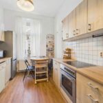 Moderne Küche mit Holzfronten, Edelstahlgeräten und einem kleinen Essbereich mit einem Tisch und Stühlen.
