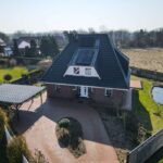 Ein modernes Einfamilienhaus mit Satteldach, umgeben von Rasenflächen und einem kleinen Teich.
