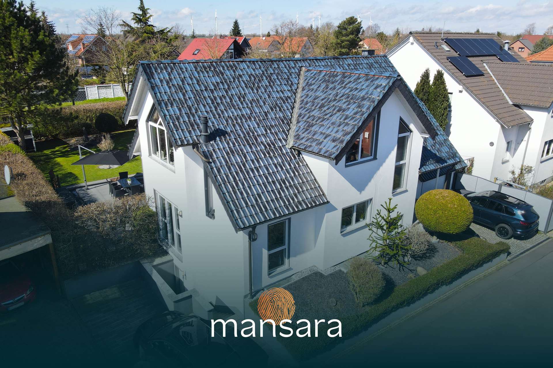 Ein modernes Einfamilienhaus mit grauem Dach, umgeben von Garten und Bäumen, in einer ruhigen Wohngegend.
