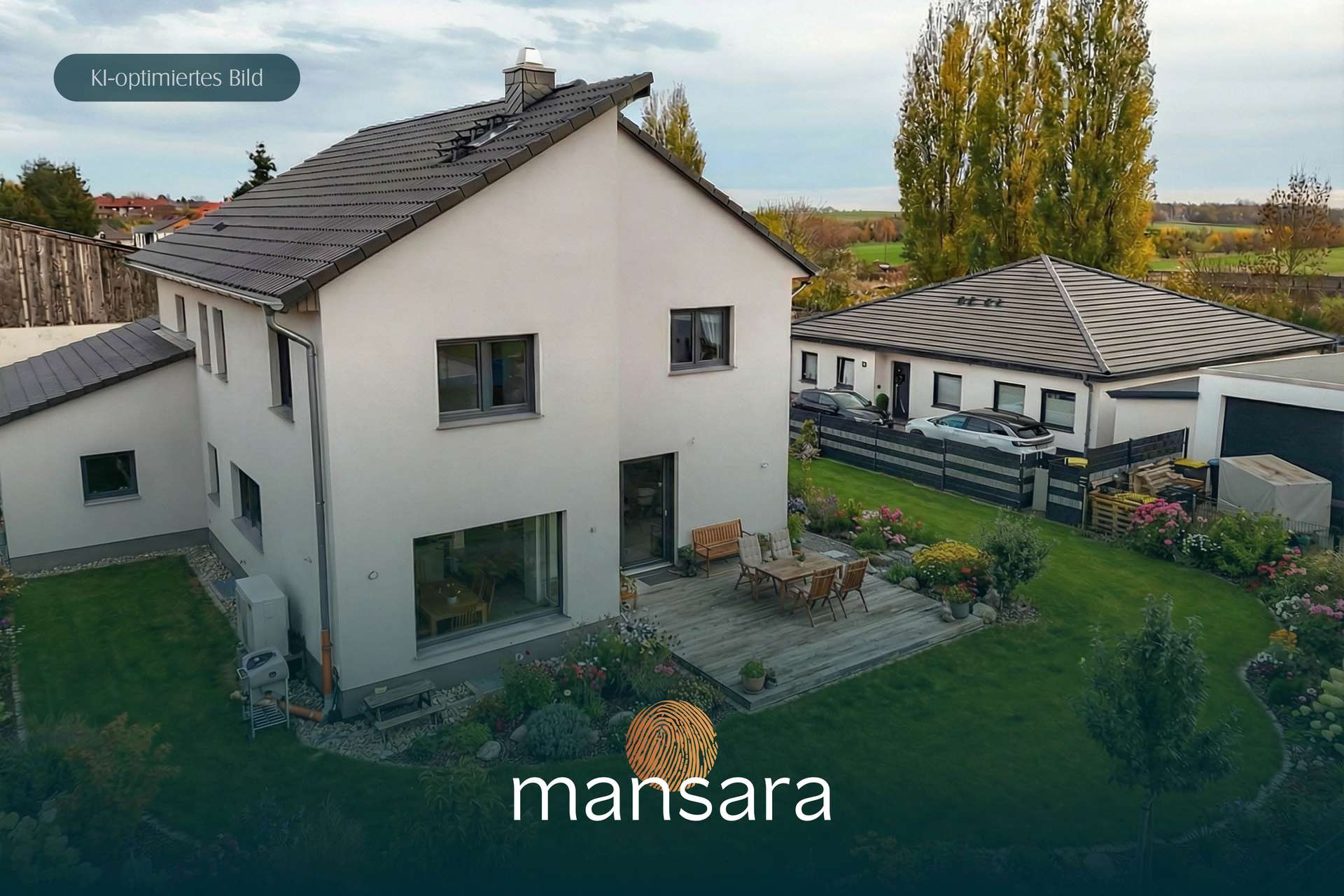 Modernes Haus mit Garten und Terrasse, umgeben von Bäumen und einem Nebengebäude, in ländlicher Umgebung.