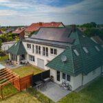Ein modernes Haus mit Solarpanelen auf dem Dach, umgeben von einem Garten und einer Terrasse.