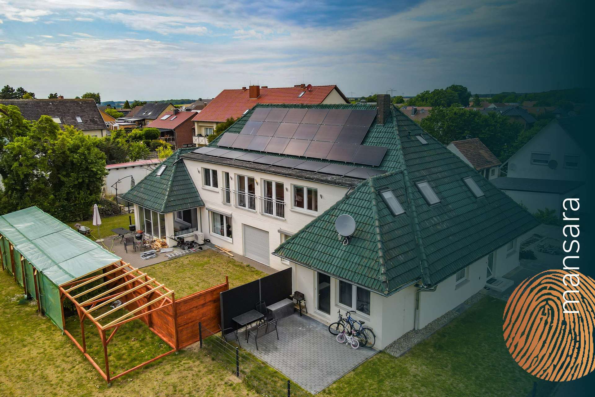 Ein modernes Haus mit Solarpanelen auf dem Dach, umgeben von einem Garten und einer Terrasse.
