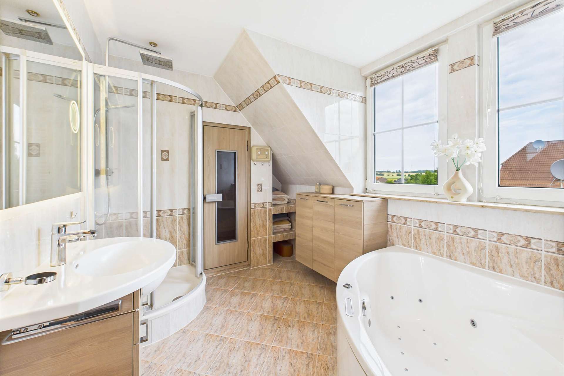 Helles Badezimmer mit Badewanne, Dusche, modernen Möbeln und großen Fenstern für Tageslicht.