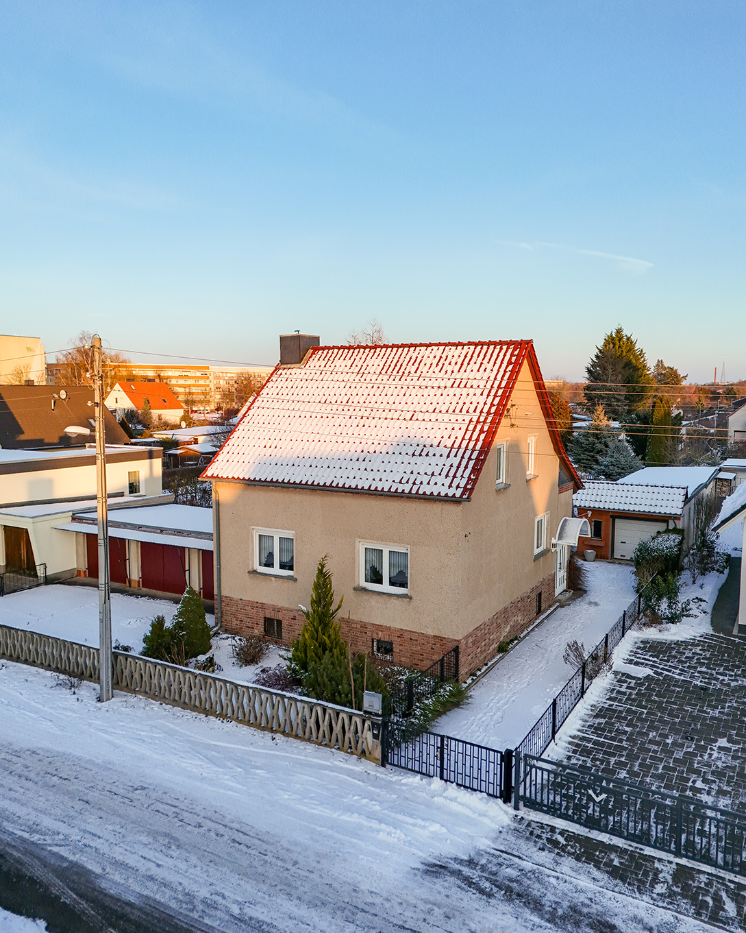 Ein zweigeschossiges Wohnhaus mit rotem Satteldach, umgeben von Schnee und winterlicher Landschaft.