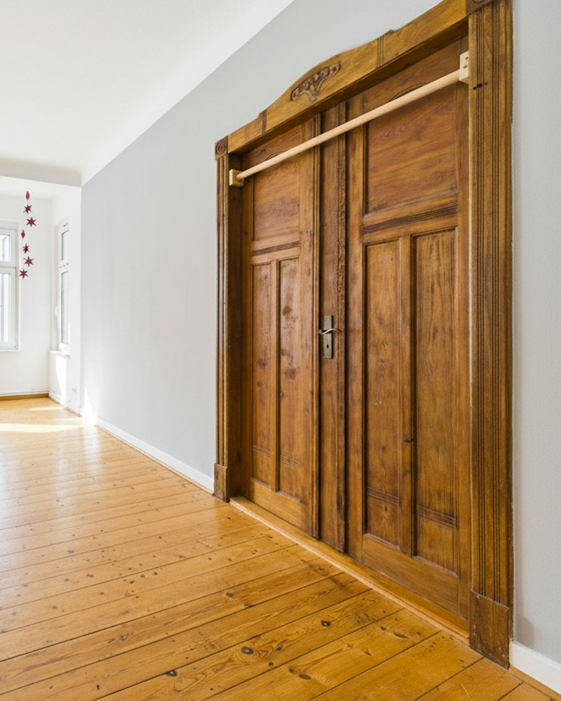 HolztĂŒr mit SchiebetĂŒrmechanismus in einem modernen Raum mit Holzboden und neutralen WĂ€nden.